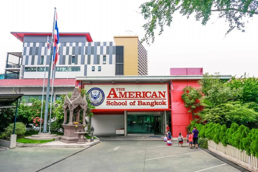 ทางเข้าด้านหน้าของโรงเรียนอเมริกันแห่งกรุงเทพฯ โดดเด่นด้วยอาคารสไตล์โมเดิร์น ธงชาติไ