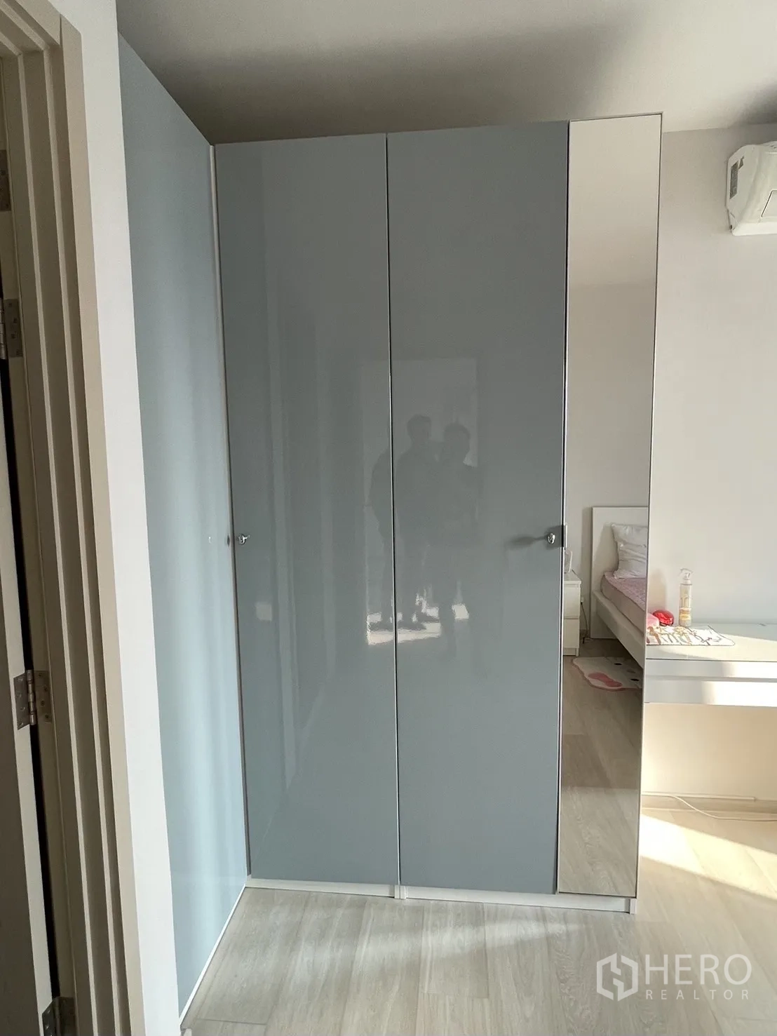 公寓 for rent in Pathum Wan, Bangkok - 走廊处的灰色高光嵌入式衣柜，旁边为浅木色地板与卧室入口。