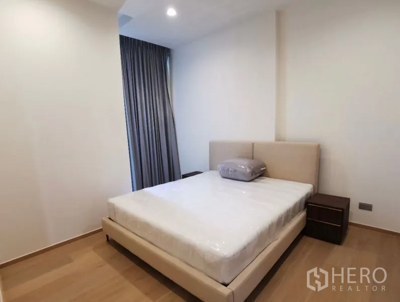 Condominium for rent in Bang Rak, Bangkok - Bright bedroom with upholstered bed, bedside tables and blackout curtains.