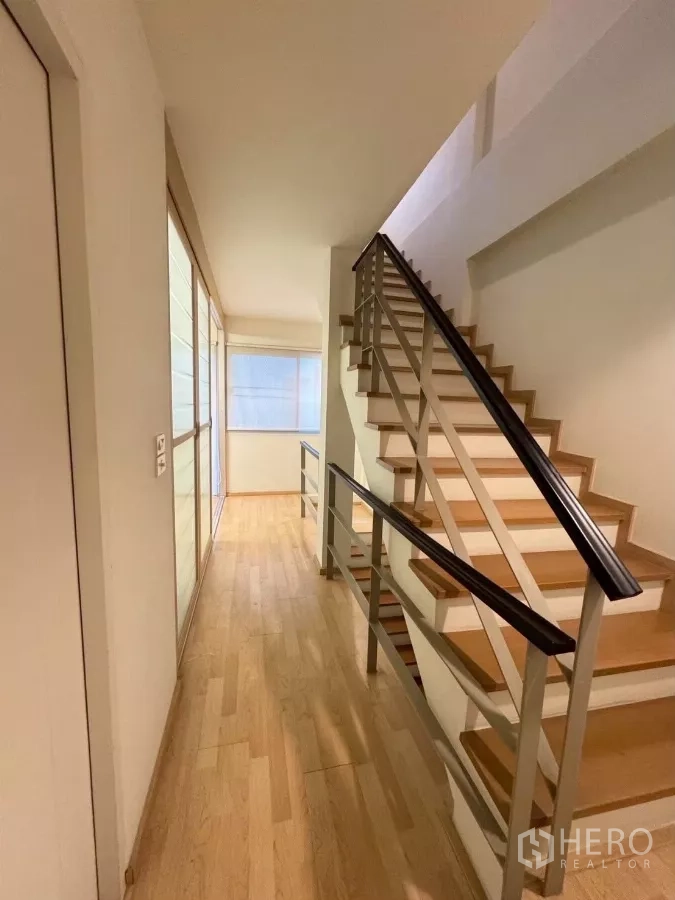 Townhouse for rent in Suan Luang, Bangkok - Staircase and hallway with wooden steps and glass sliding doors.