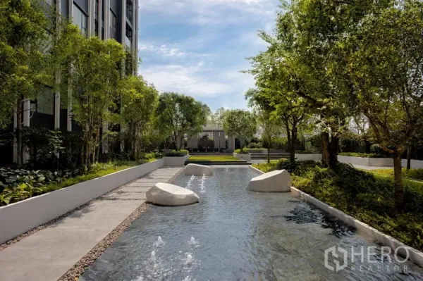 公寓 出租在Pathum Wan, Bangkok - 静谧水景，踏步石与小喷泉，被绿树与步道环绕。