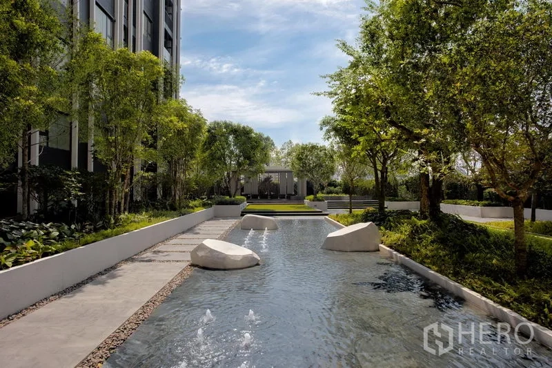 公寓 出租在Pathum Wan, Bangkok - 静谧水景，踏步石与小喷泉，被绿树与步道环绕。