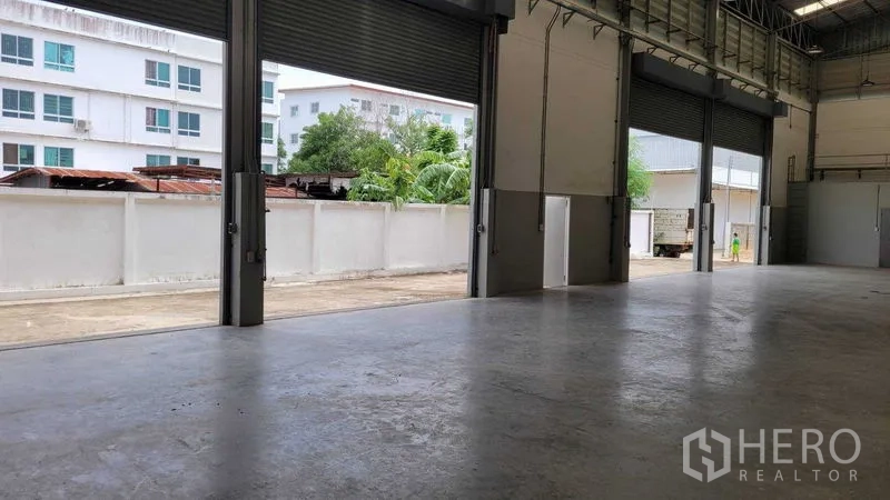 คลังสินค้า ให้เช่าในSaphan Sung, Bangkok - ช่องเปิดกว้างพร้อมประตูม้วนหลายชุดออกสู่ลานคอนกรีต