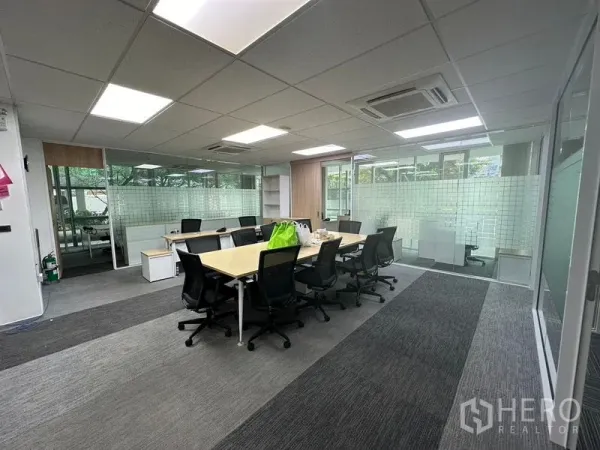 Office Space for rent - Central collaboration room with boardroom table, glass partitions, and LED light panels.