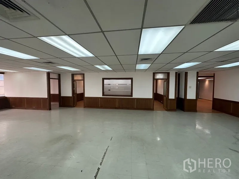 办公空间 出租在Watthana, Bangkok - 大型开放办公区，格栅吊顶灯，通往多间侧房的门洞。