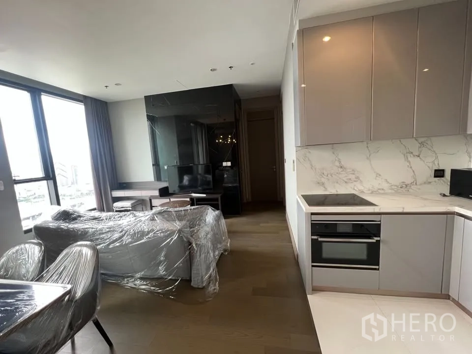 公寓 出租在Huai Khwang, Bangkok - 从厨房望向客厅，沙发、电视柜与大窗引入充足采光。