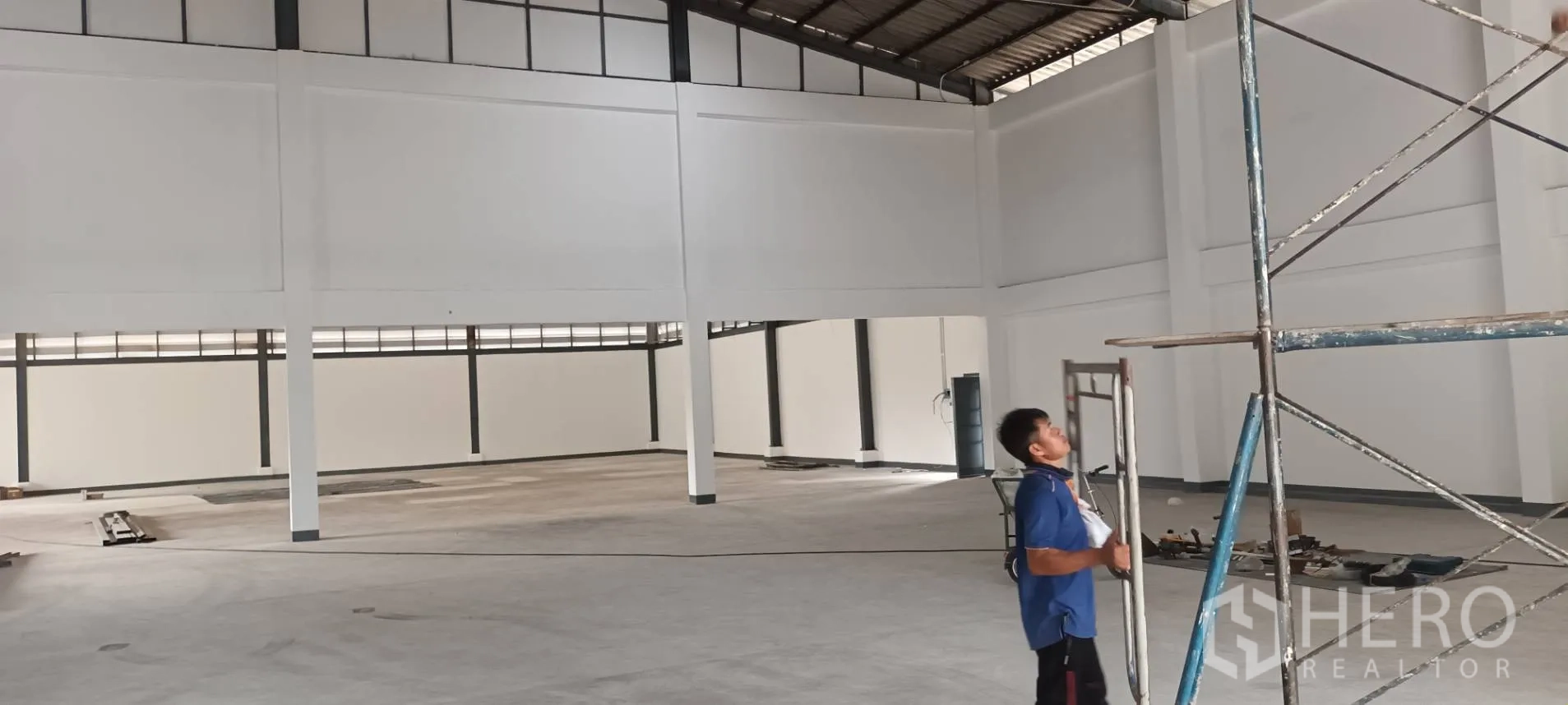 Warehouse for rent in Phra Pradaeng, Samut Prakan - High-roof interior with steel trusses and clerestory windows providing daylight across the floor.