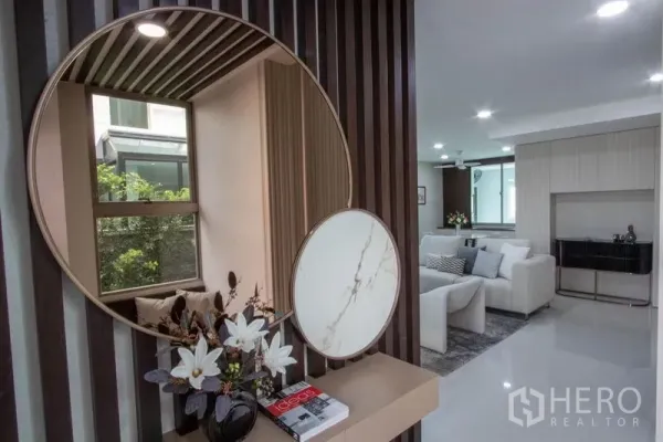 บ้าน ขายในSaphan Sung, Bangkok - โถงทางเข้าพร้อมกระจกเงากลม ผนังไม้ระแนง มองเชื่อมไปยังห้องนั่งเล่นสว่าง