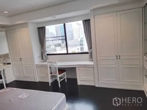 Condominium for rent in Sathon, Bangkok - Bright bedroom with built-in wardrobes and a long study desk beneath a large window with city views.