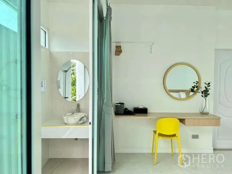 Detached House for rent in Lat Krabang, Bangkok - Work desk with round mirror beside an ensuite vanity separated by a sliding curtain.