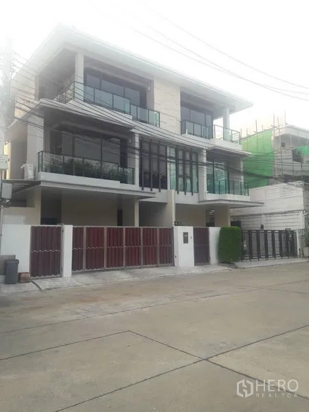 Townhouse for rent or sale in Chatuchak, Bangkok - Modern three‑storey townhouse facade with glass balconies and gated parking.