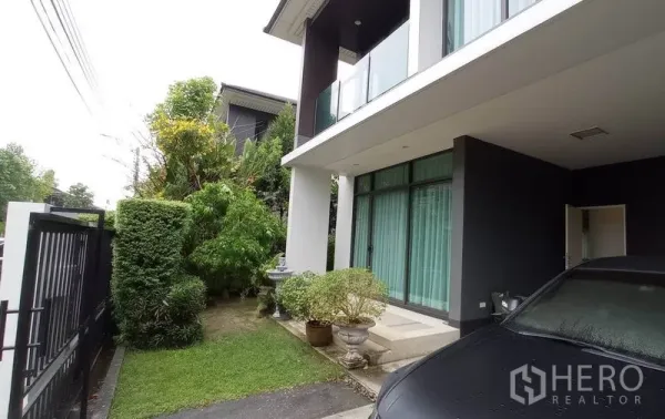 独立式住宅 出租在Bang Kapi, Bangkok - 侧庭草坪与灌木，旁接有顶车棚与入户门廊。