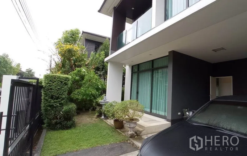 独立式住宅 出租在Bang Kapi, Bangkok - 侧庭草坪与灌木，旁接有顶车棚与入户门廊。