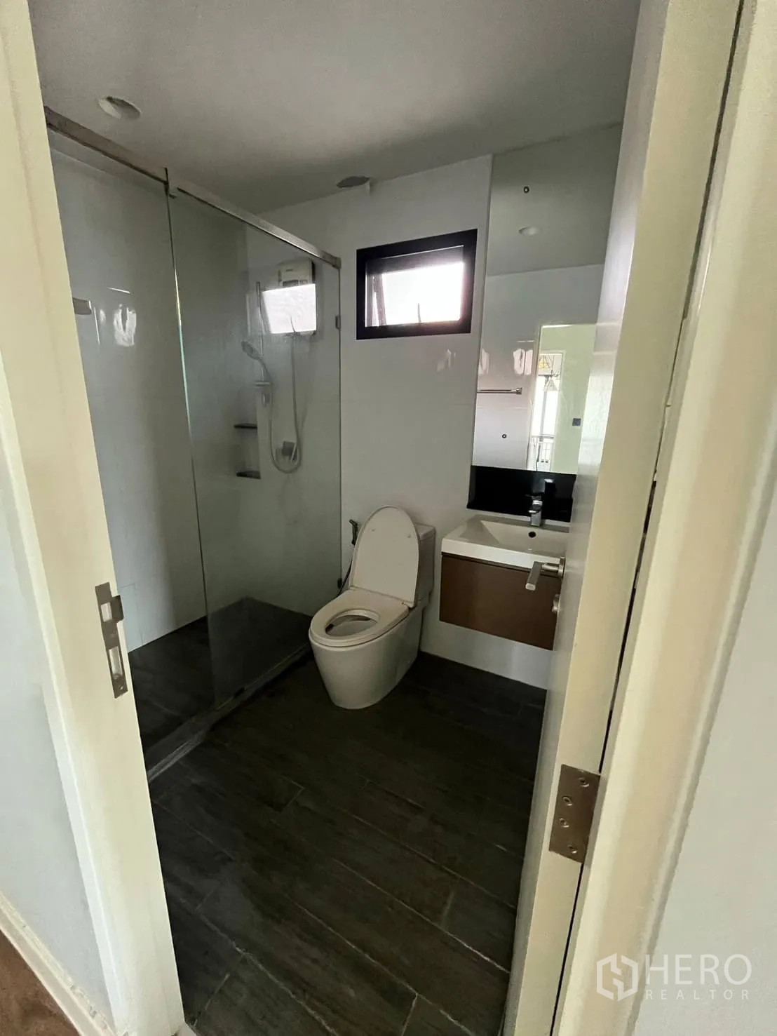 Detached House for rent or sale in Lam Luk Ka, Pathum Thani - Bathroom with glass-enclosed shower, vanity and dark tiled floor.