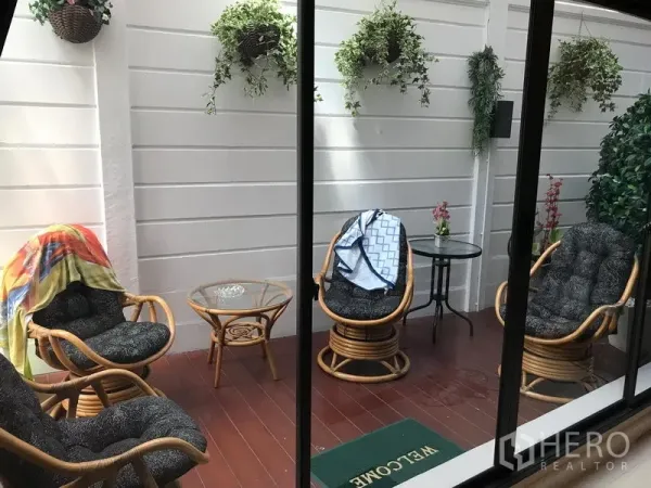 Townhouse for rent or sale in Chatuchak, Bangkok - Enclosed patio with rattan lounge chairs, hanging plants and wood decking.