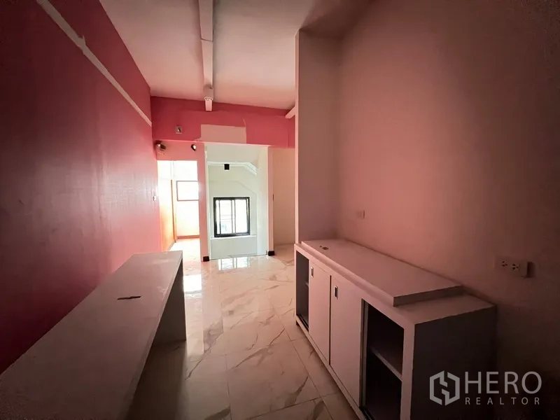Shophouse for rent in Watthana, Bangkok - Upper-floor corridor with pink accent wall and built-in white cabinetry.