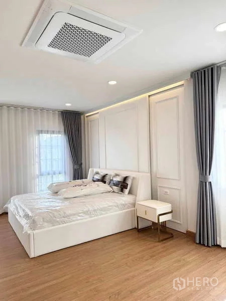 บ้าน ให้เช่าหรือขายในBang Phli, Samut Prakan - ห้องนอนหลักผนังตกแต่ง เตียงสีขาว แอร์ฝังฝ้า พื้นไม้ และหน้าต่างมุม