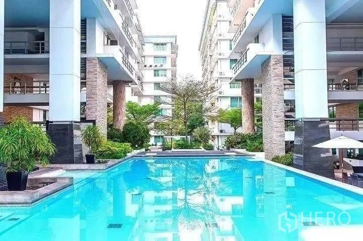 Condominium for rent in Khlong Toei, Bangkok - Outdoor communal swimming pool set between low-rise condo buildings with greenery.