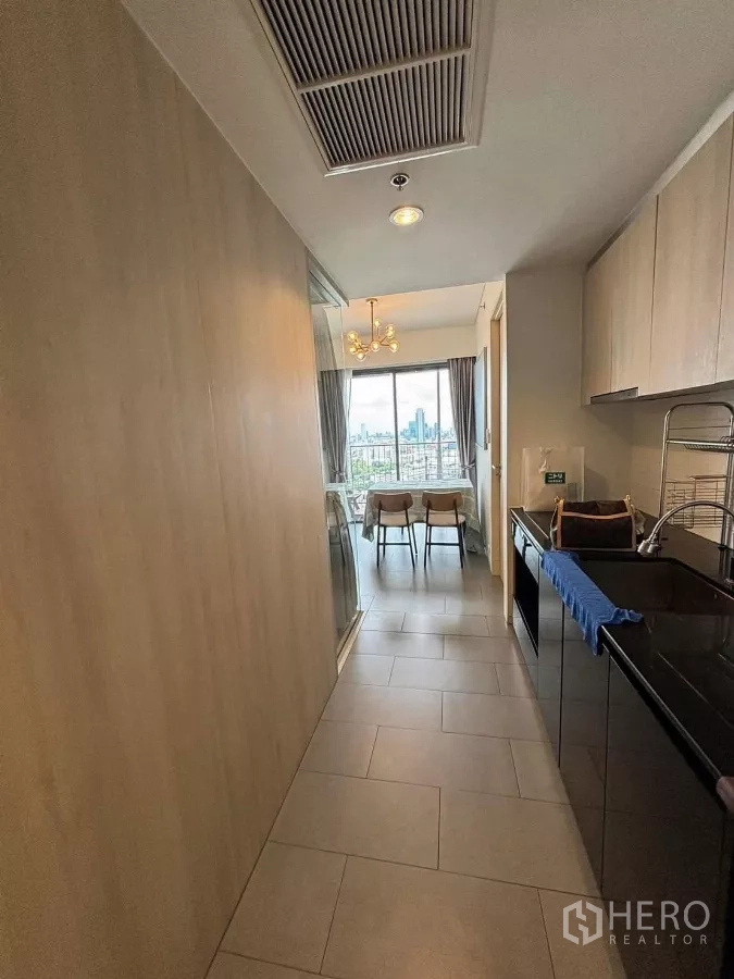 Condominium for rent or sale in Phaya Thai, Bangkok - Hallway kitchen view toward the dining area with city skyline visible through wide windows.