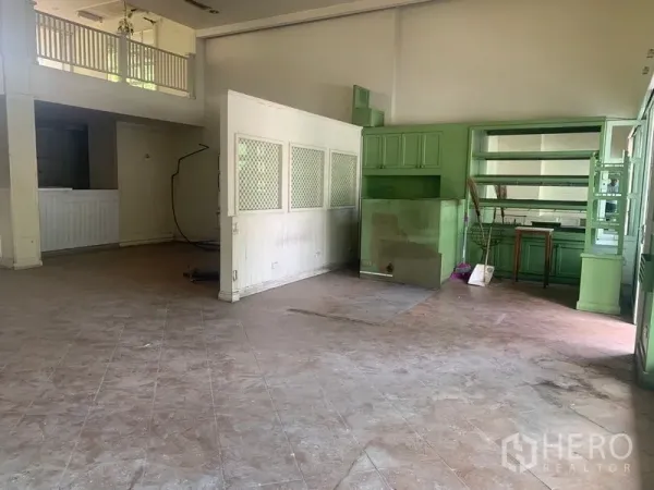 Shophouse for rent in Watthana, Bangkok - Spacious interior with high ceiling and green built-in shelving units.