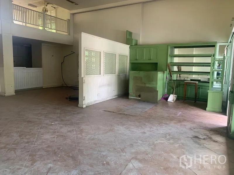 Shophouse for rent in Watthana, Bangkok - Spacious interior with high ceiling and green built-in shelving units.