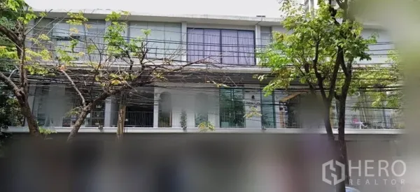 Office Space for rent in Khlong Toei, Bangkok - Low-rise building exterior with large glass windows, balcony railings and street trees in the Sukhumvit area.