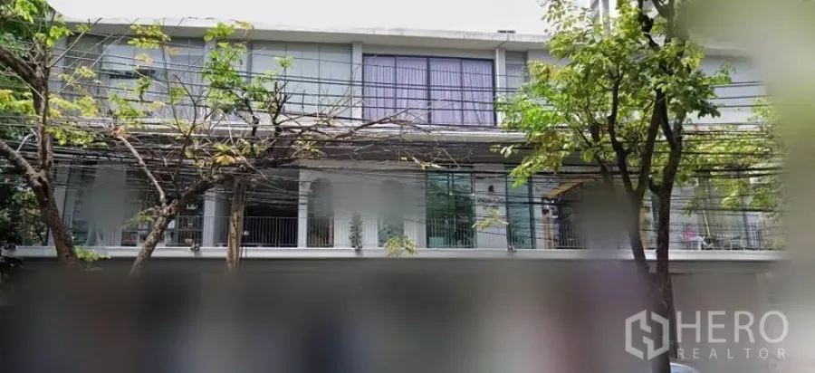 Office Space for rent in Khlong Toei, Bangkok - Low-rise building exterior with large glass windows, balcony railings and street trees in the Sukhumvit area.