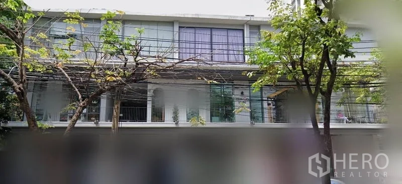 Office Space for rent in Khlong Toei, Bangkok - Low-rise building exterior with large glass windows, balcony railings and street trees in the Sukhumvit area.