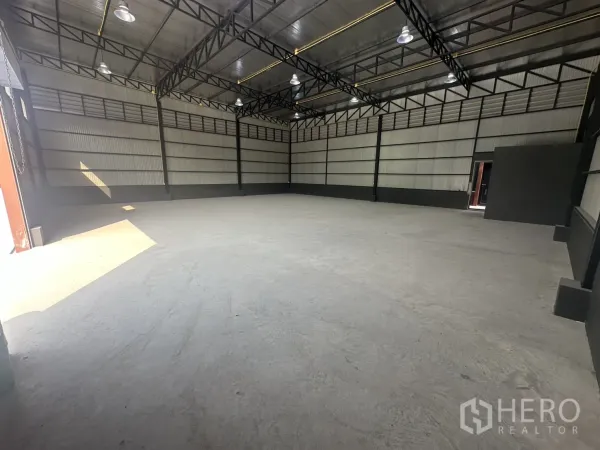 Warehouse for rent in Prawet, Bangkok - Corner view of the warehouse highlighting insulated roof, black trim and smooth concrete flooring.