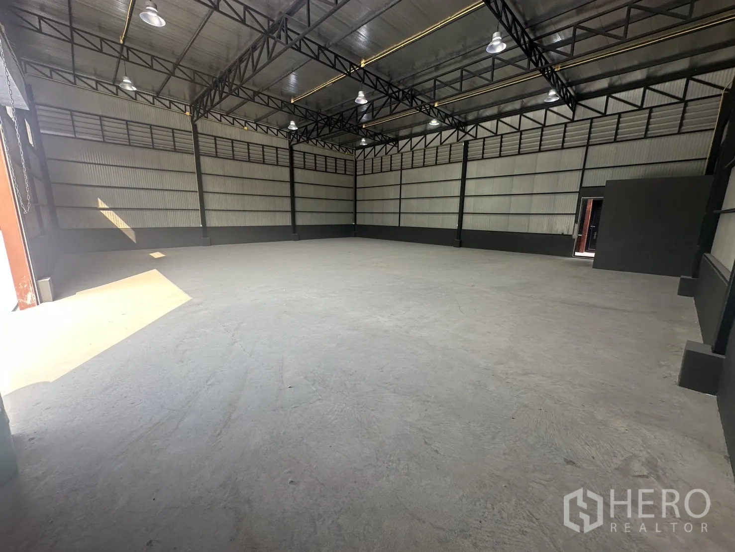 Warehouse for rent in Prawet, Bangkok - Corner view of the warehouse highlighting insulated roof, black trim and smooth concrete flooring.