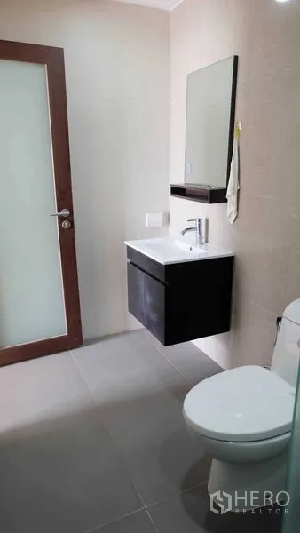 公寓 出租在Phaya Thai, Bangkok - 整洁的浴室，悬挂式洗手台、镜子和坐便器，配磨砂玻璃门。