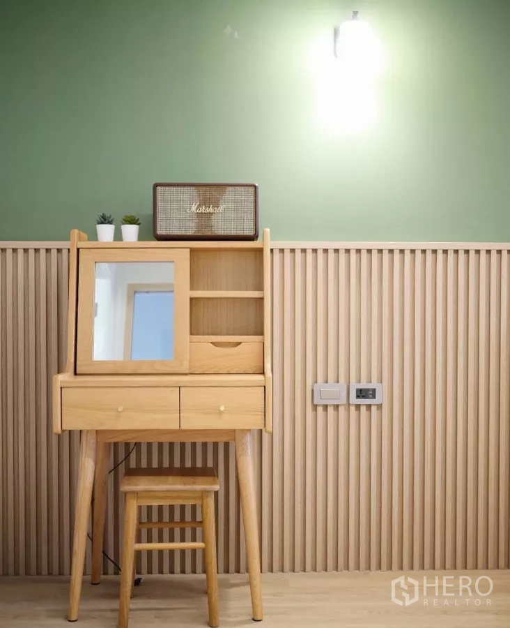 Townhouse for rent in Watthana, Bangkok - Minimal wooden vanity and stool set against a green wall with vertical battens.