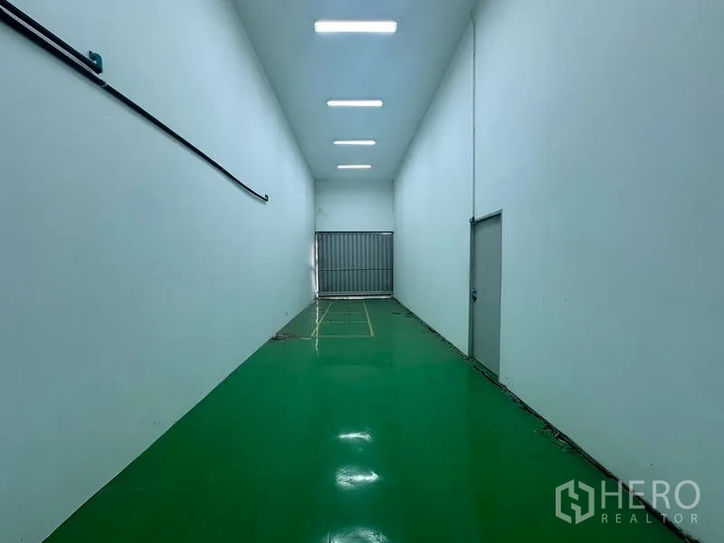 Warehouse for rent in Suan Luang, Bangkok - Long loading corridor with roller shutter and high ceiling.