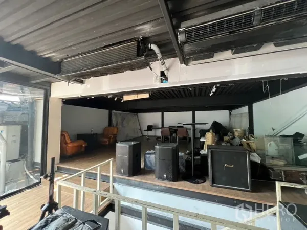 พื้นที่ขายปลีก ให้เช่า - ชานยกระดับสไตล์อินดัสเทรียลในร้าน มีลำโพง เก้าอี้หนัง และผนังกระจกด้านข้าง