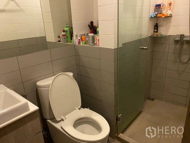 Condominium for sale in Phra Khanong, Bangkok - Modern bathroom with glass-enclosed shower, toilet and tiled walls