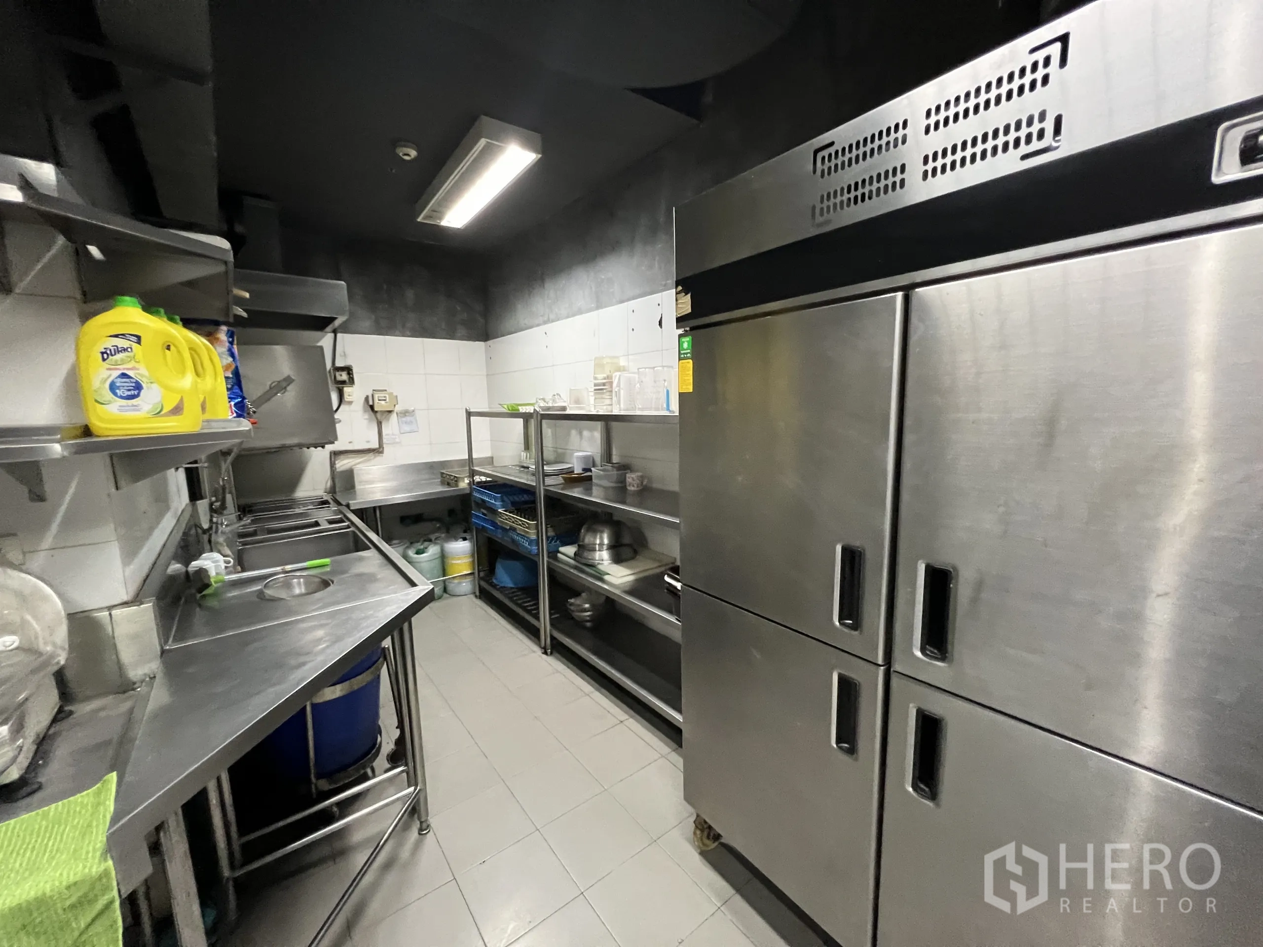Retail Space for rent in Watthana, Bangkok - Dishwashing and pantry area with stainless sinks, shelving, and double-door fridge.