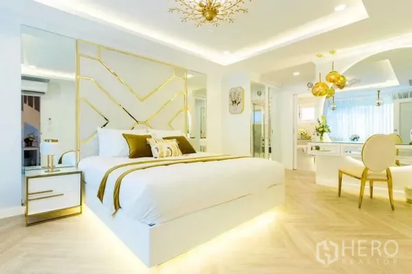 Townhouse for rent in Lat Phrao, Bangkok - Modern master bedroom with gold accents, mirrored feature wall and soft cove lighting.