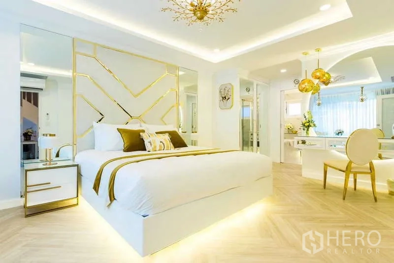 Townhouse for rent in Lat Phrao, Bangkok - Modern master bedroom with gold accents, mirrored feature wall and soft cove lighting.