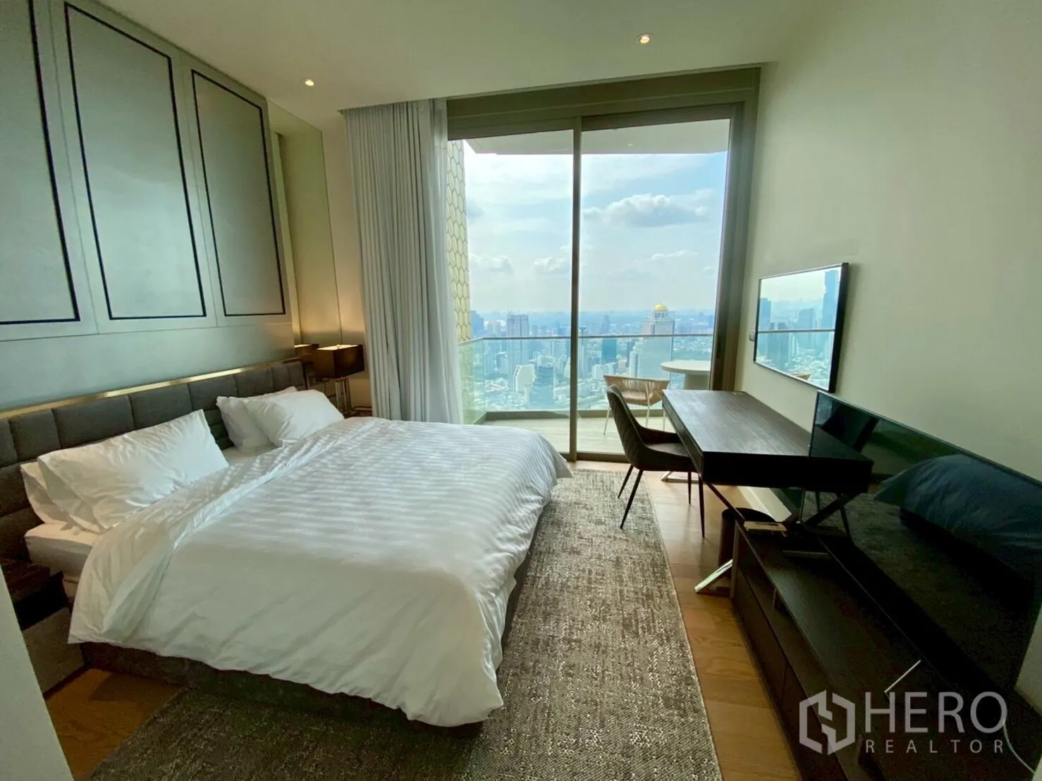 公寓 出租在Khlong San, Bangkok - 卧室连通阳台，设书桌与壁挂电视，远眺城市与河流。