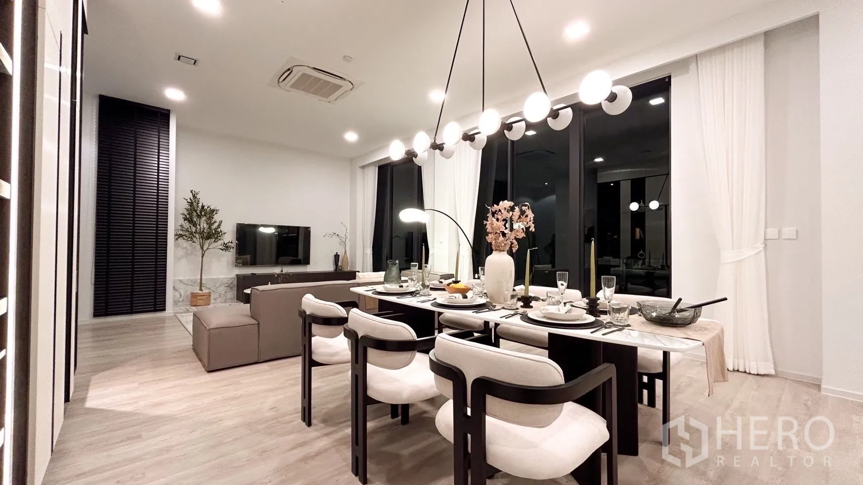 Detached House for rent in Saphan Sung, Bangkok - Bright dining room and lounge at night with floor-to-ceiling windows and chandelier.