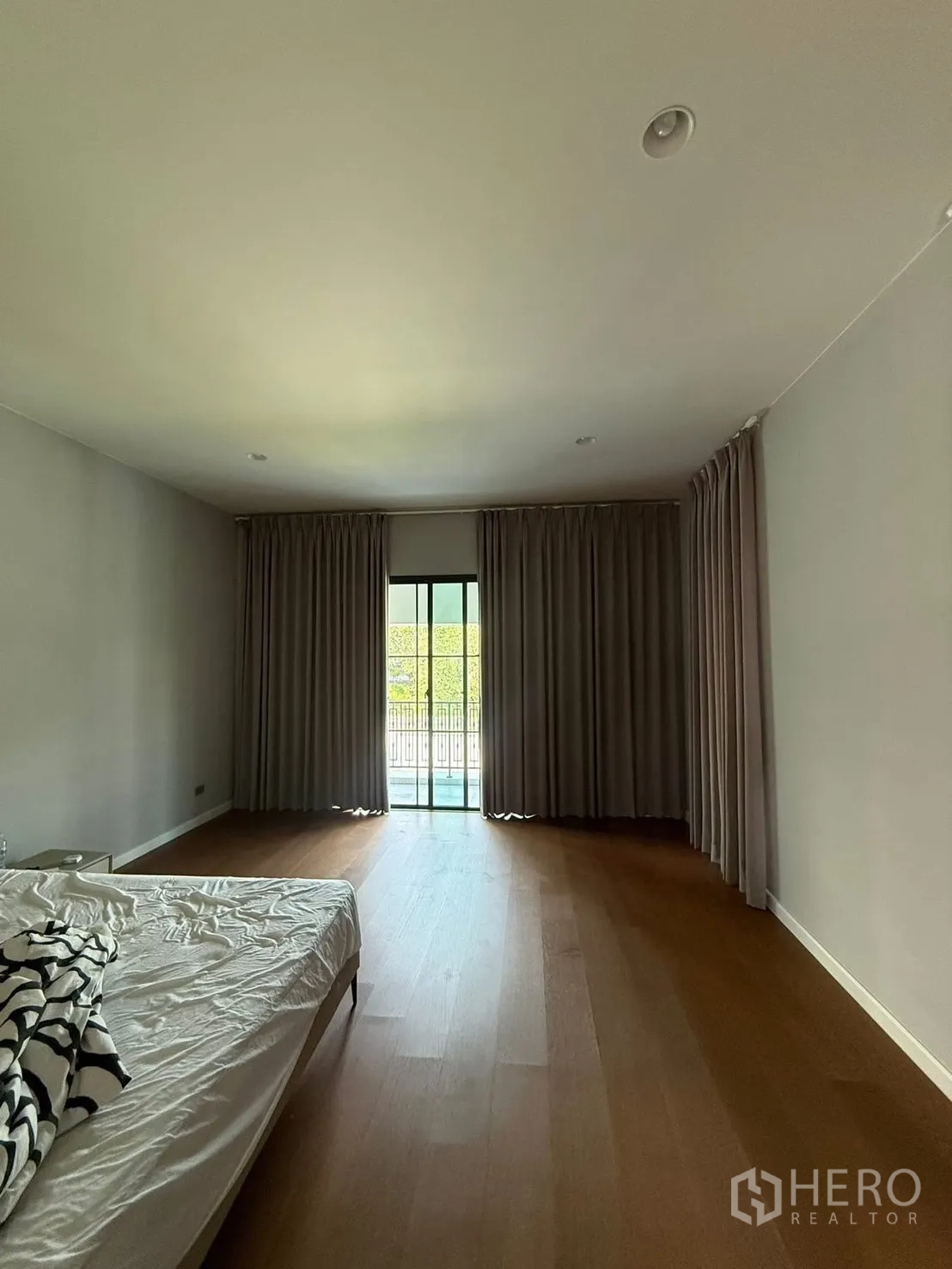 独栋房屋 for rent in Bang Kapi, Bangkok - 主卧配落地窗帘与木地板，可直通阳台。