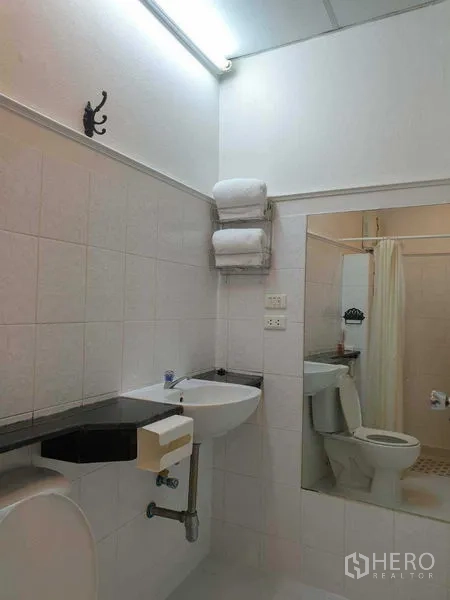 零售空间 出租在Huai Khwang, Bangkok - 整洁的瓷砖卫浴，含洗手盆、大镜子、座厕与淋浴区。