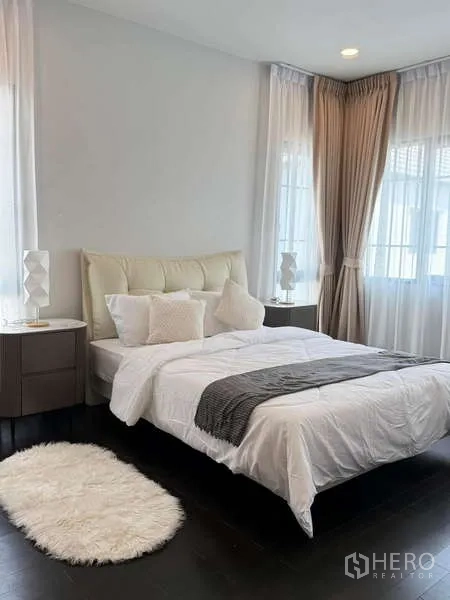 Detached House for rent or sale in Bang Phli, Samut Prakan - Guest bedroom with large windows, neutral bedding, shag rug and dark wood flooring.