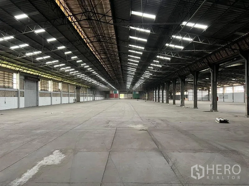 Warehouse for rent in Bang Pa-in, Phra Nakhon Si Ayutthaya - Long central aisle inside a warehouse with symmetrical roof lights and containers at the far end.