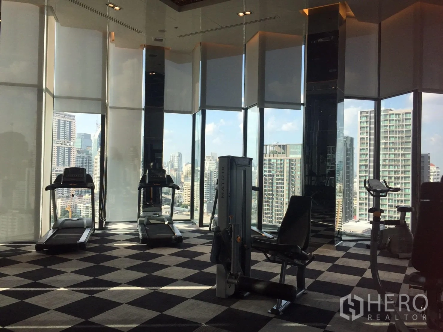 Condominium for rent in Khlong Toei, Bangkok - Skyline gym with cardio and weight machines facing floor-to-ceiling windows.
