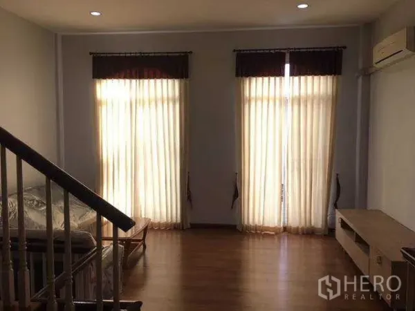 带办公室的家 出租在Wang Thonglang, Bangkok - 曼谷家庭办公楼的楼上起居室，木地板、落地窗帘与空调及楼梯扶手。