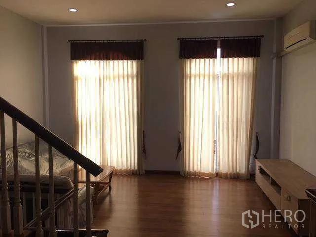 带办公室的家 出租在Wang Thonglang, Bangkok - 曼谷家庭办公楼的楼上起居室，木地板、落地窗帘与空调及楼梯扶手。
