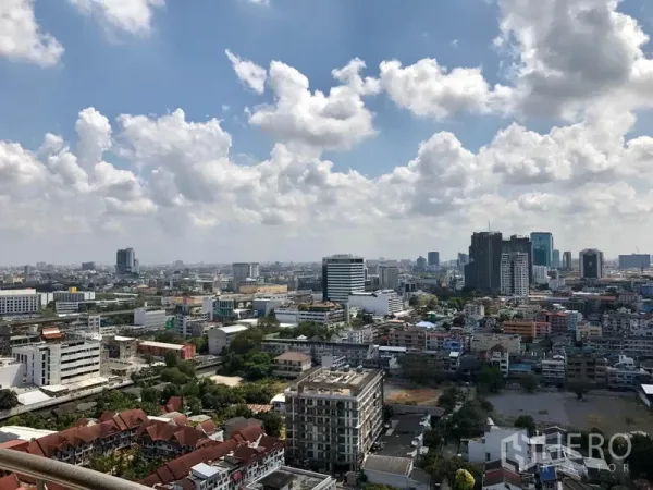Condominium for rent in Watthana, Bangkok - Panoramic Bangkok skyline view from an upper-floor balcony with clouds overhead.