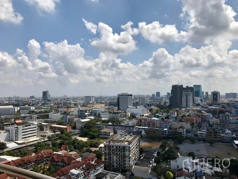 Condominium for rent in Watthana, Bangkok - Panoramic Bangkok skyline view from an upper-floor balcony with clouds overhead.