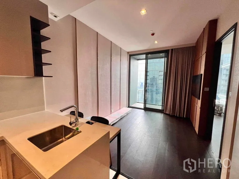 Condominium for rent in Watthana, Bangkok - Living area leading to a balcony with city view beside the kitchen peninsula.